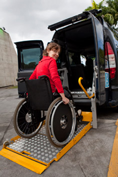 Woman in wheelchair using a lift to get into a van